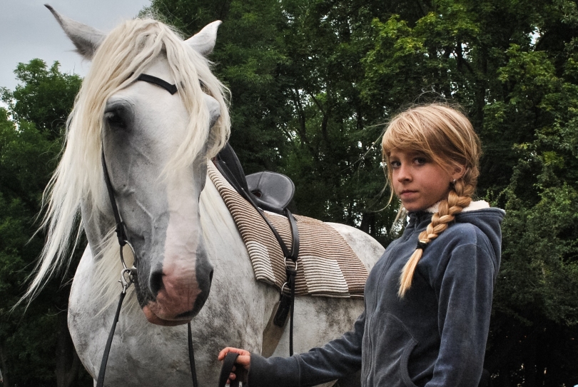 A girl stands with her horse at the top of Petrin Hill.