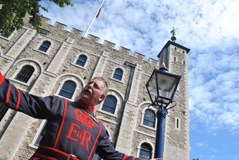 A Yeoman Warder entertains a small crowd on a guided tour of the Tower of London on a hot July day.
